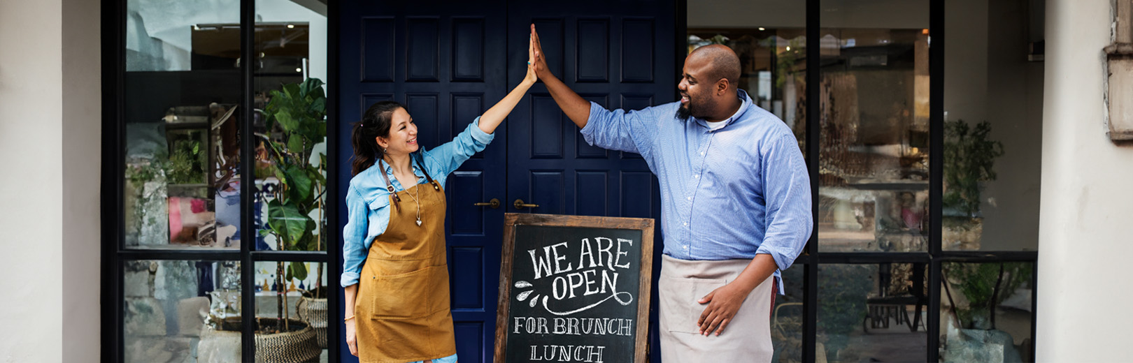 Small business owners high-five in front of purchased building