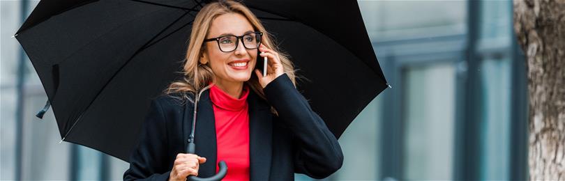 Busineswoman_Smiles_Talking_On_Phone_While_Carrying_Umbrella