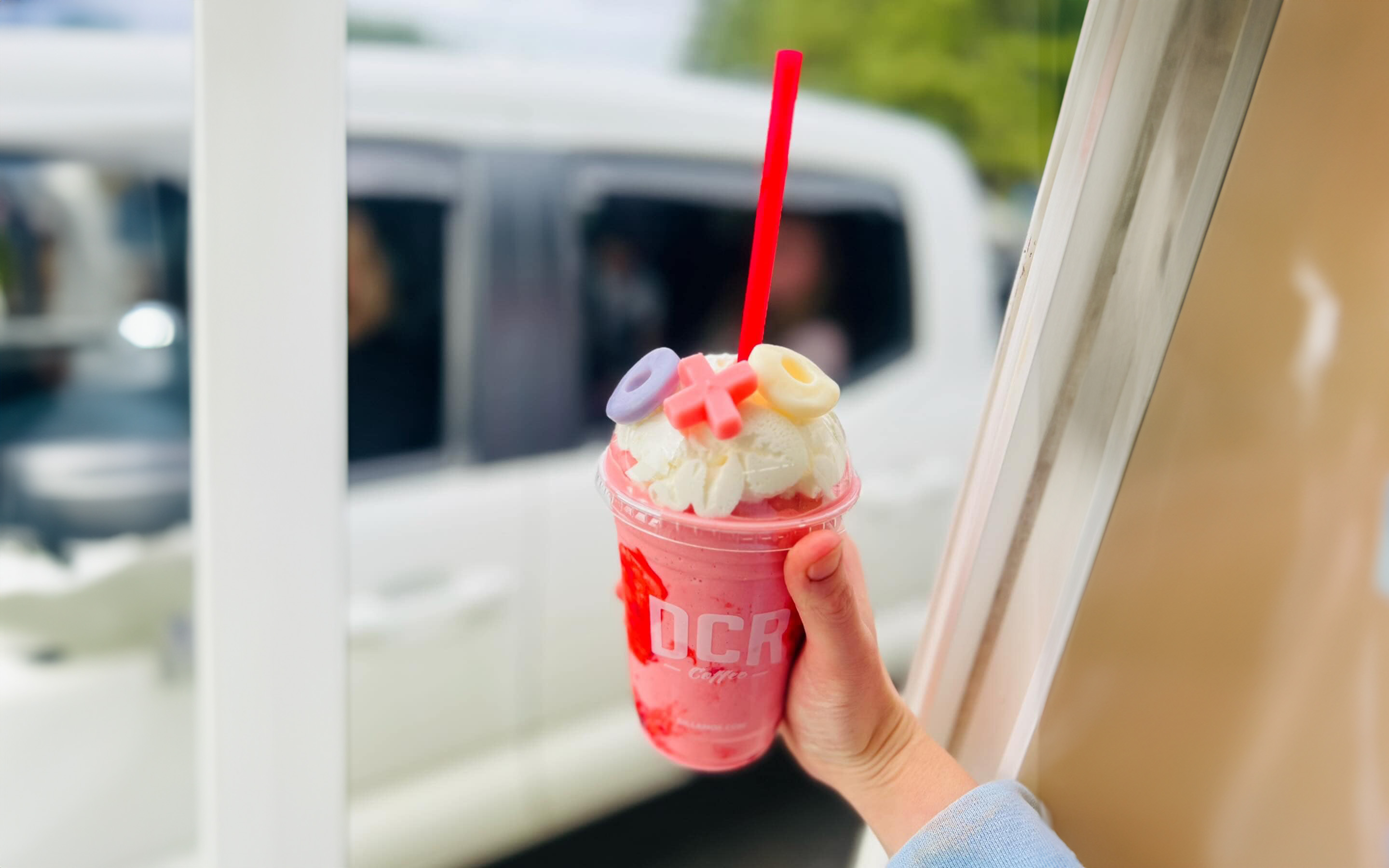 A pink energy drink being handed through the drive thru window at Bug and Buf's Espresso